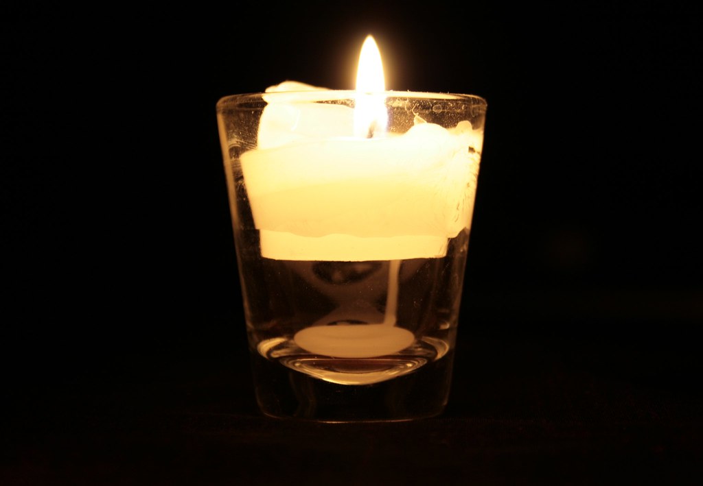 Vela encendida en la penumbra, símbolo de acompañamiento y calma